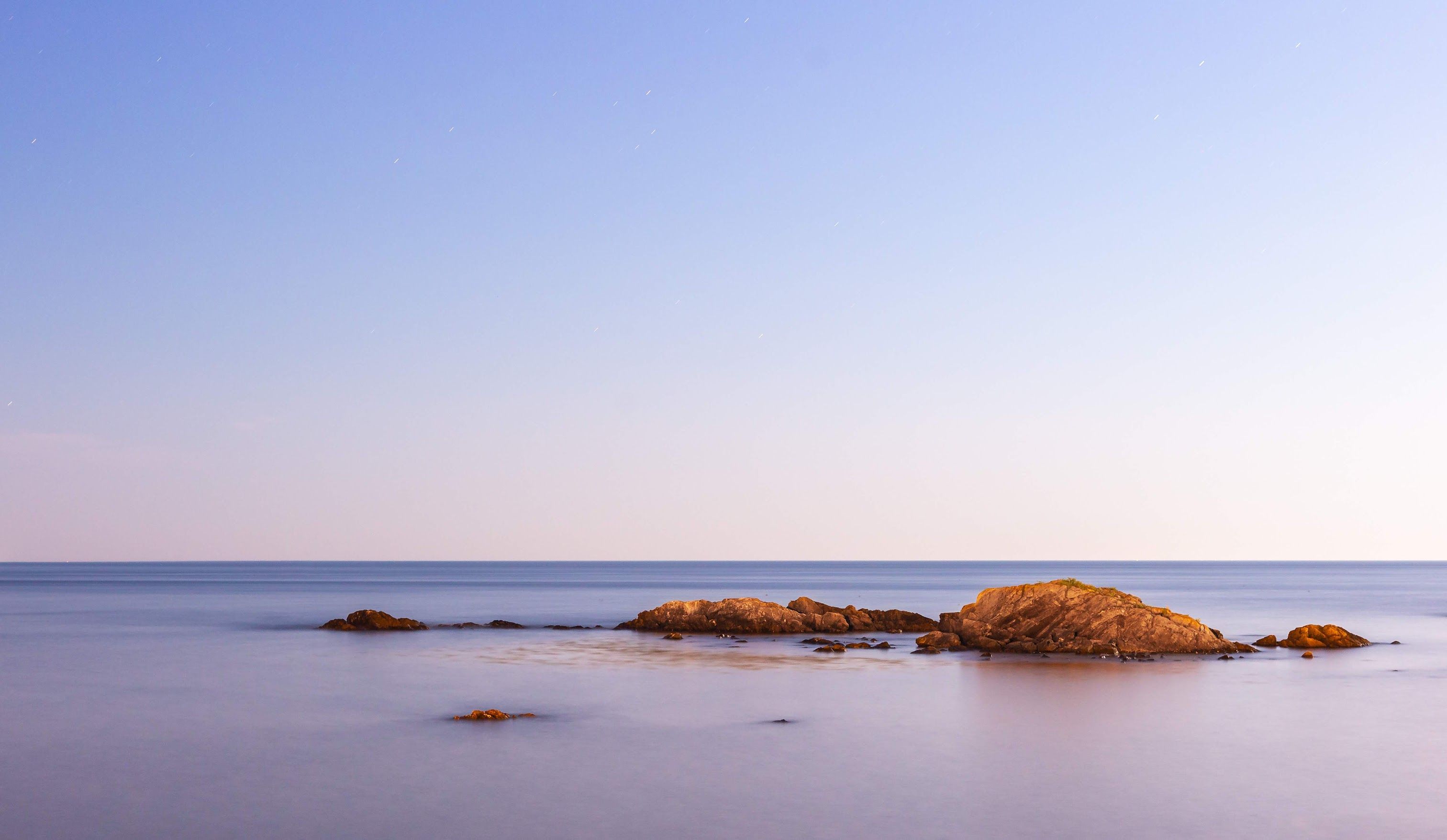 A rocky shoreline with a large rock in the water.